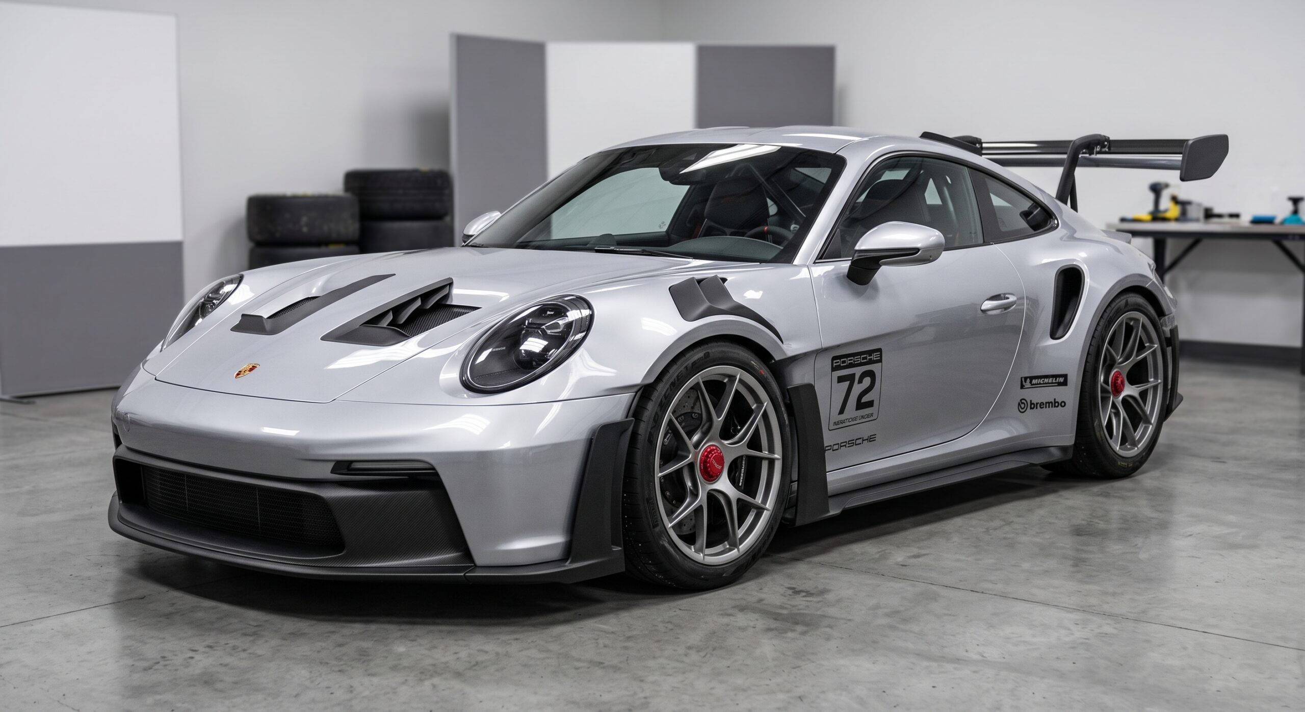 ガレージ内に置かれたシルバーのポルシェ911 GT3 RS。アグレッシブなボンネットダクトや大型リアウィング、ゼッケン72のサイドデカールが目を引くハイパフォーマンスカーです。
